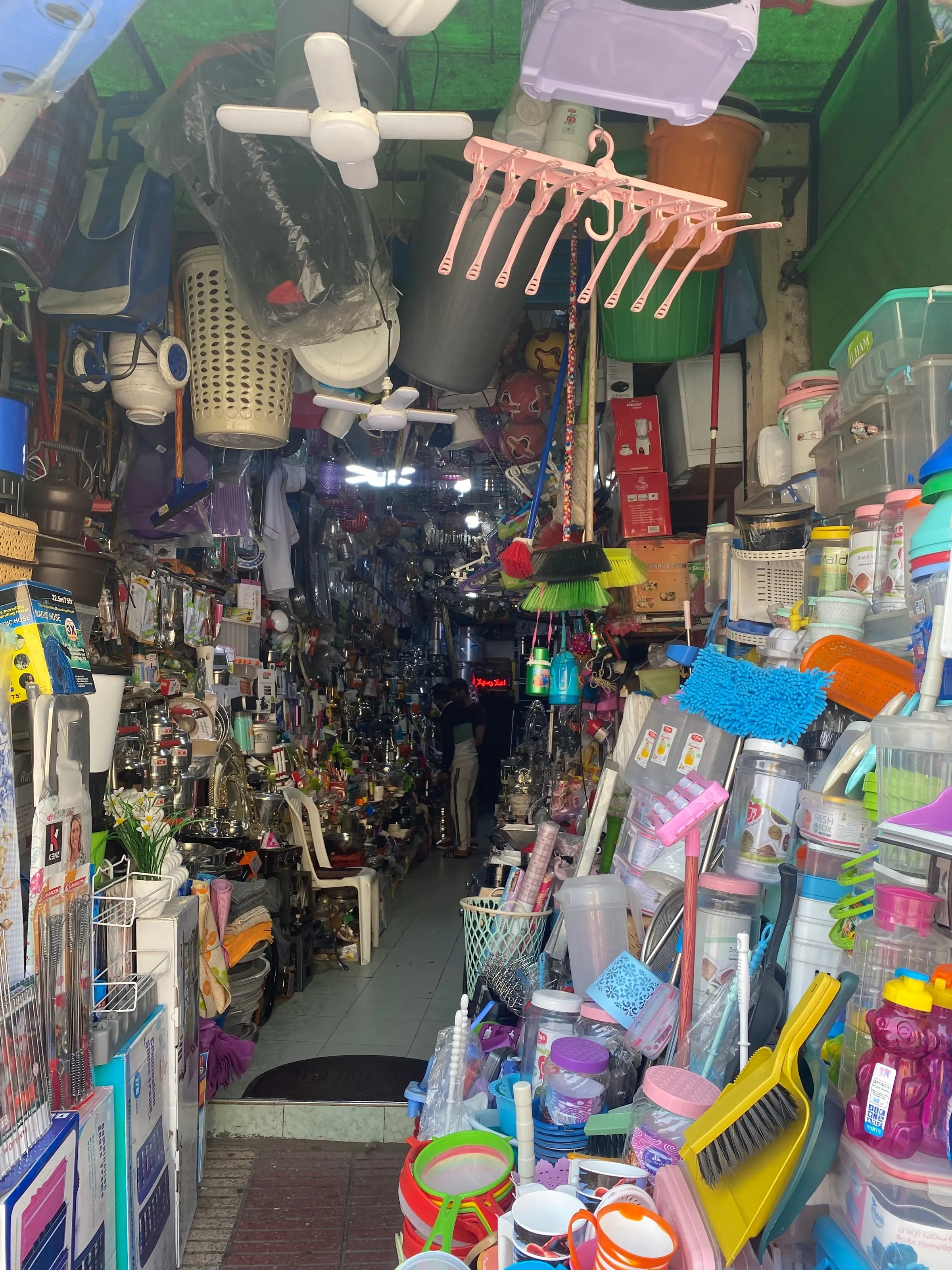 A narrow shop packed from floor to ceiling with kitchenware, baskets and colourful household goods.