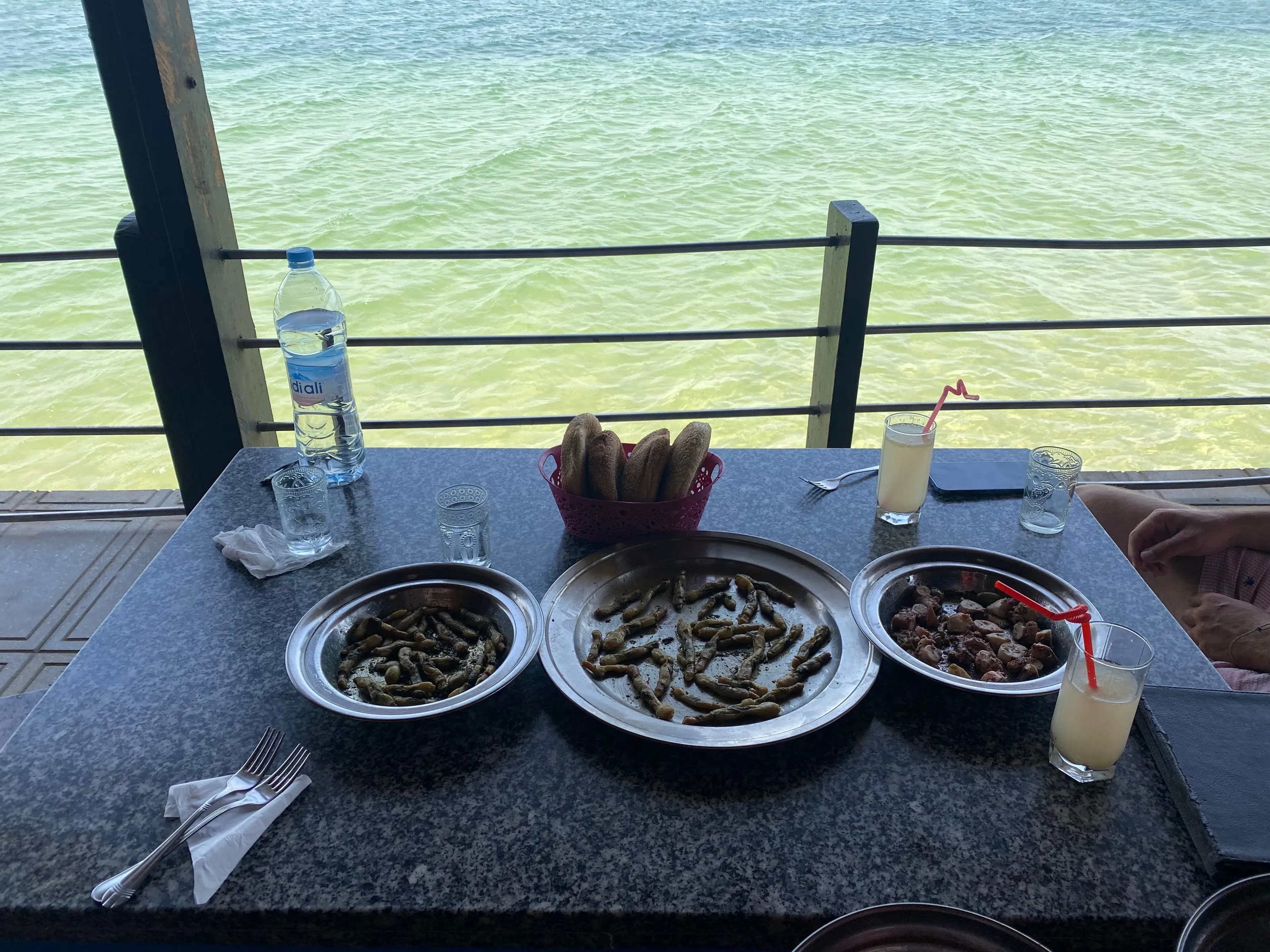 Platters of seafood, bread and drinks on a table laid beside Dakhla lagoon.