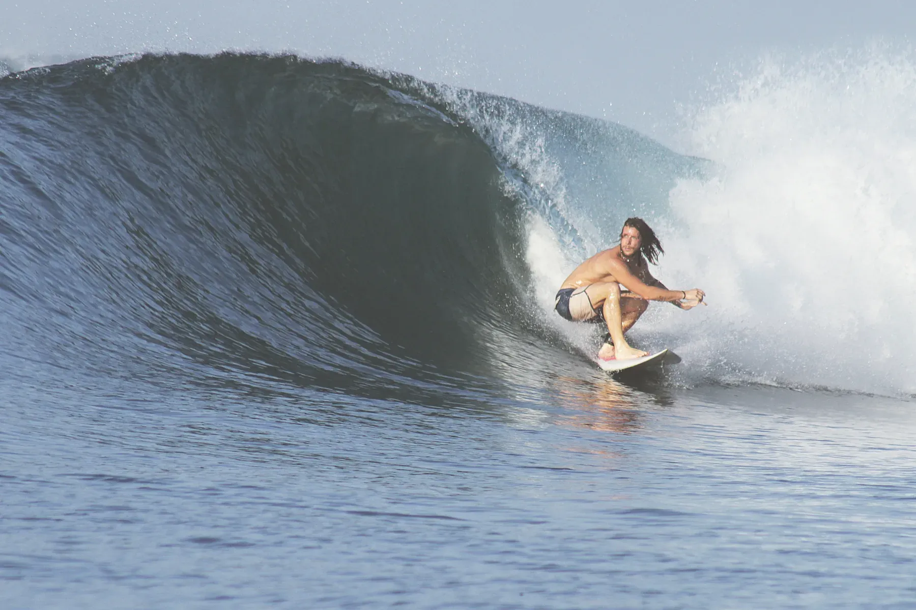 A surfer crouches on a board in a wave in Sumbawa, at a spot not identified as Scar Reef